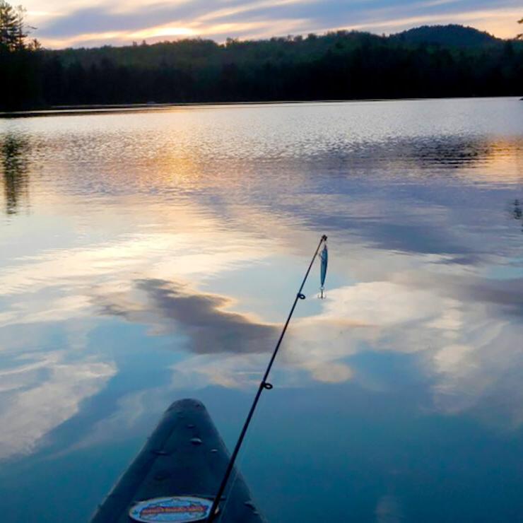 the bow of a fishing boat at dusk showing a pole and recently-caught fish